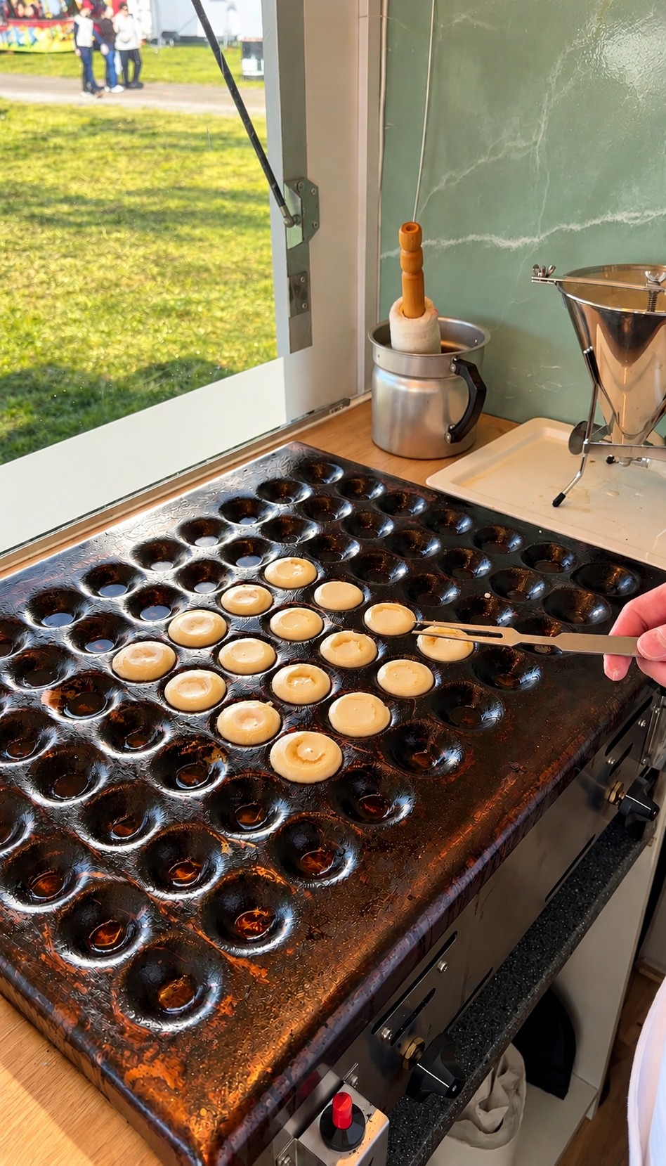 Poffertjes bliver friskbagt og vendt på pladen i Oline’s dessertvogn